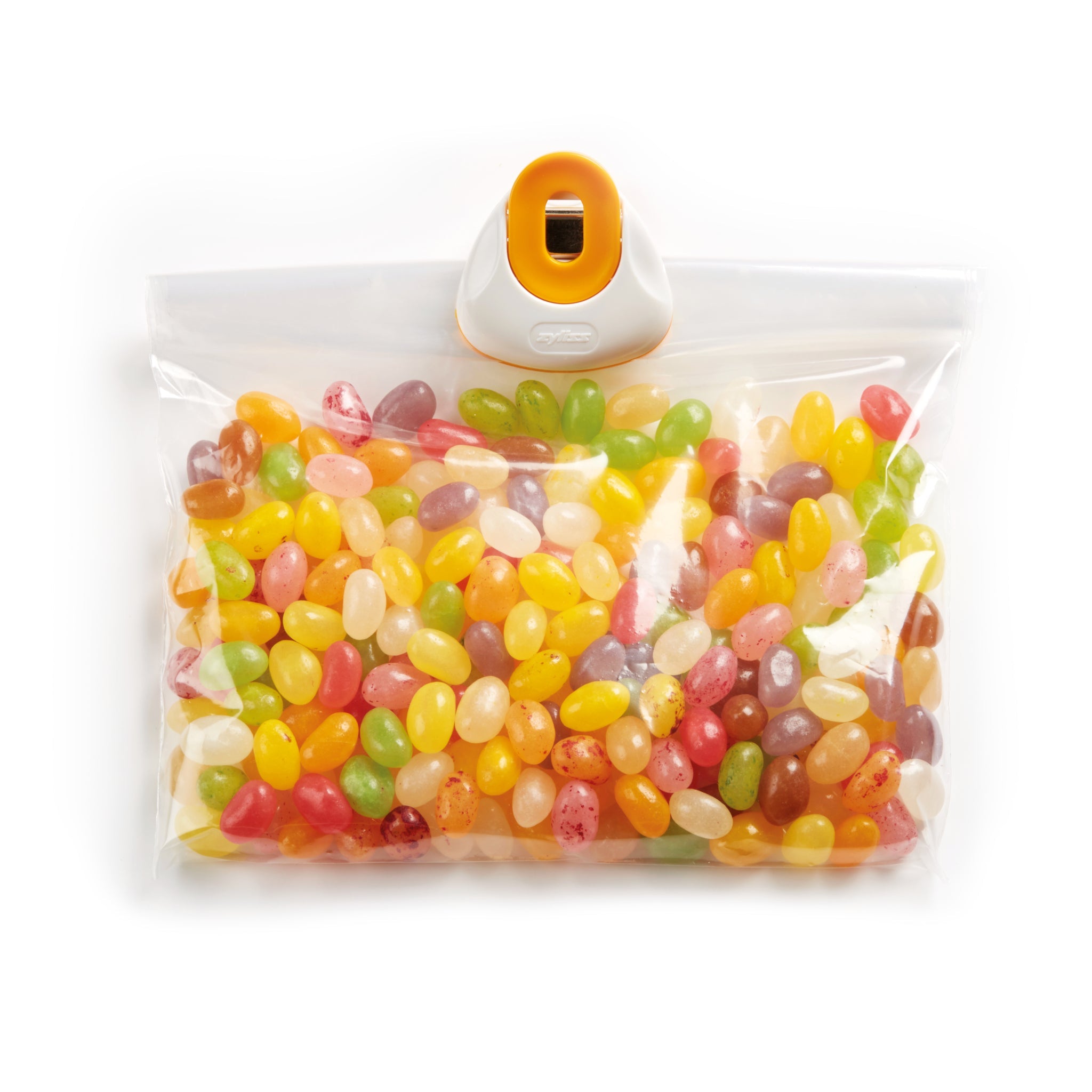 A clear resealable plastic bag of assorted colorful jelly beans is sealed with a Zyliss Clip-All Bag Clip (Mixed Sizes) in orange and white—a kitchen essential for preventing food spillage. 