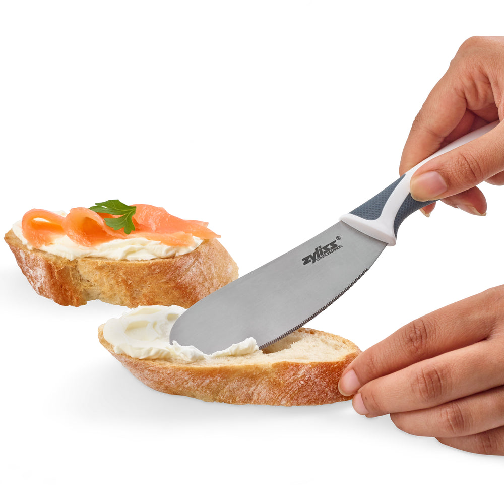 The Zyliss Comfort Spreading Knife 10.5cm / 4¼ features a stainless steel rounded blade and an ergonomic white and dark gray handle, shown on a plain light background. 