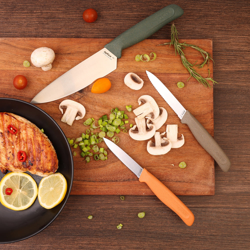 The Zyliss 3 Piece Knife Set includes chef and paring knives with green, gray, and orange handles, each with a protective sheath, displayed side by side on a light background for a vibrant kitchen look.