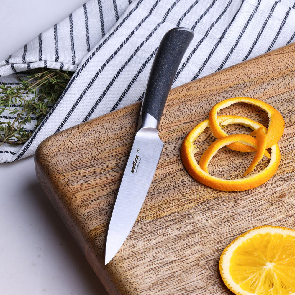 The Zyliss Comfort Pro Utility Knife 14cm/5½", crafted from German stainless steel with a gray ergonomic handle, is shown vertically against a plain light background.
