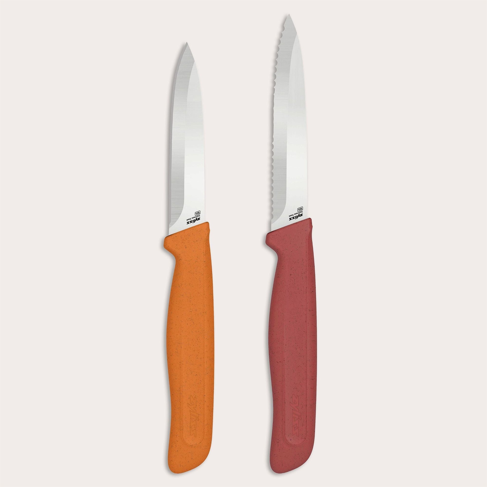 The Zyliss Classic 2 Piece Paring Knife Set includes two kitchen knives: one with an orange ergonomic handle and straight-edged stainless steel blade, and another with a red handle and serrated stainless steel blade.