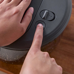 A person presses the one-handed pump on the lid of a black Zyliss Swift Dry Salad Spinner while holding the lid steady with their other hand.