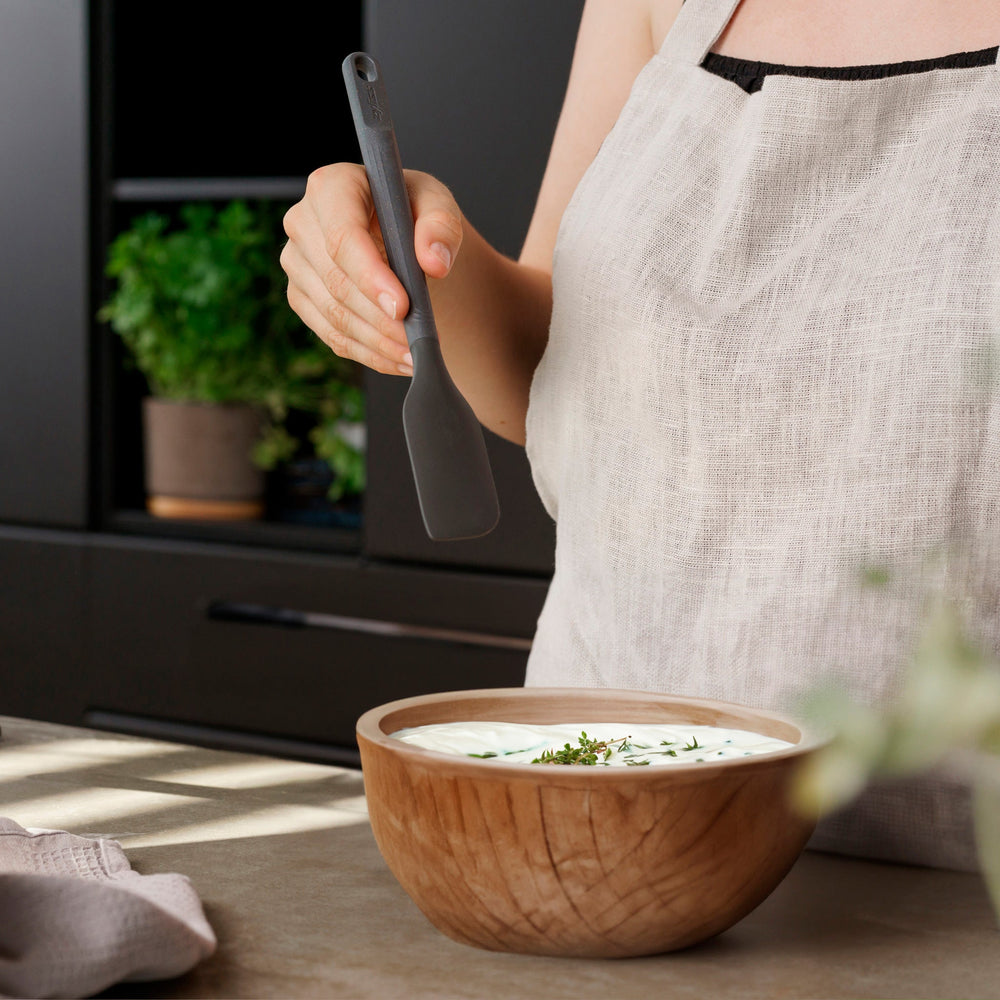 The Zyliss Spatula, featuring a long handle and flat, angled grey silicone head, is displayed against a plain white background.