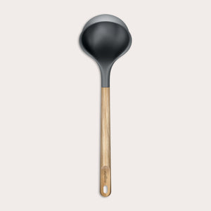 The Zyliss Oak Wood Ladle Large is black with a gray rim and a long oak handle featuring a hanging hole, displayed on a plain light background.