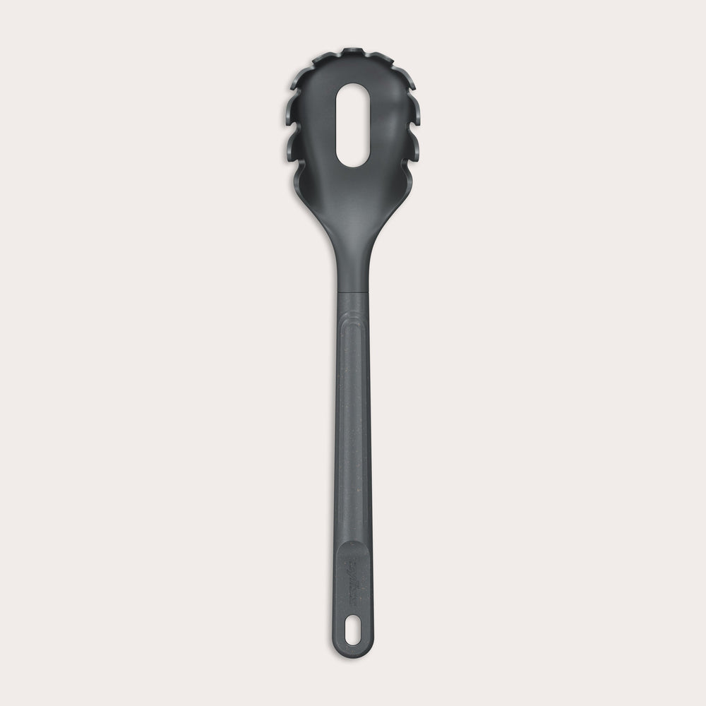 The Zyliss Spaghetti Server is a black, heat-resistant utensil with a long handle and slotted, rounded head featuring prongs for ideal portion control, shown isolated on a light background. 