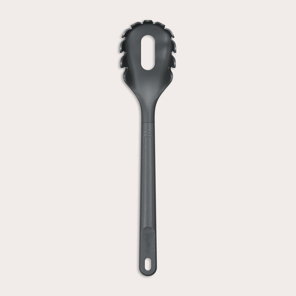 The Zyliss Spaghetti Server is a black, heat-resistant utensil with a long handle and slotted, rounded head featuring prongs for ideal portion control, shown isolated on a light background. 