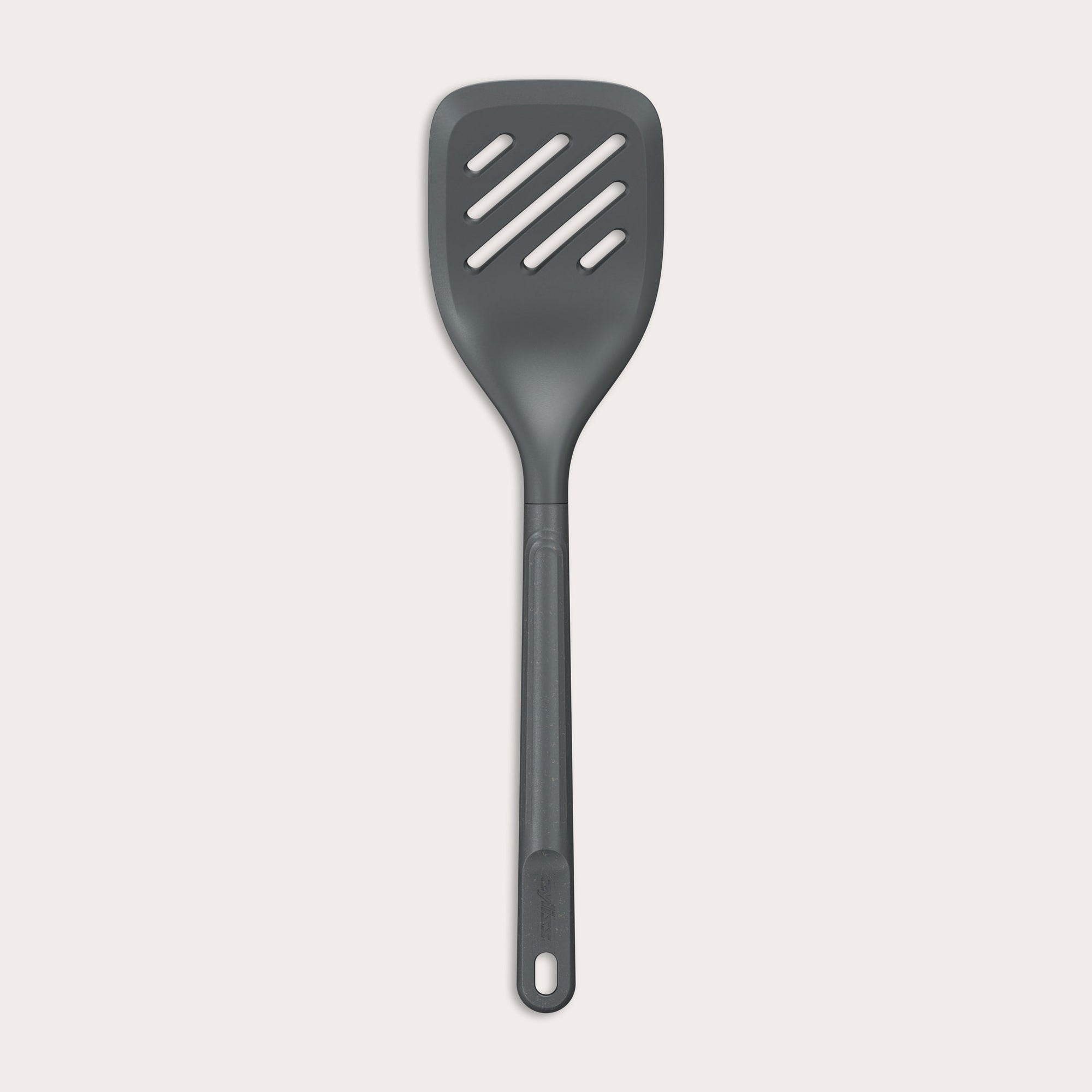 The Zyliss Slotted Turner, shown in black with three diagonal slots and an ergonomic handle, features a heat-resistant design for safe cooking or flipping food. Displayed against a plain white background. 