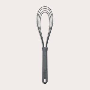 The Zyliss Flat Whisk Silicone features a black, heat-resistant silicone design with a long handle and looped wires, displayed on a plain light background. 