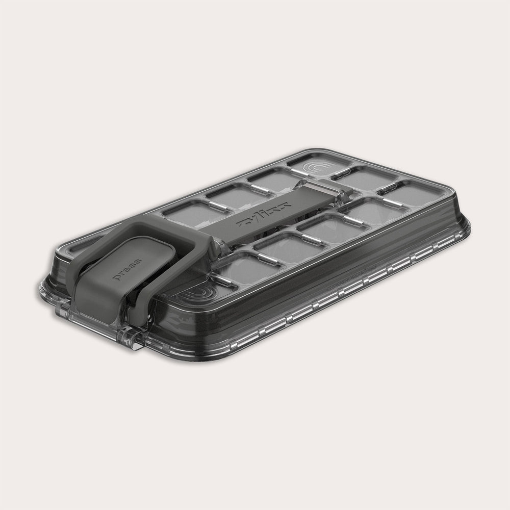 A rectangular, transparent plastic lid for the Zyliss Press & Pull Ice Cube Tray with a gray foldable handle, textured grid pattern, and "Zyliss" embossed on top, shown on a light background.