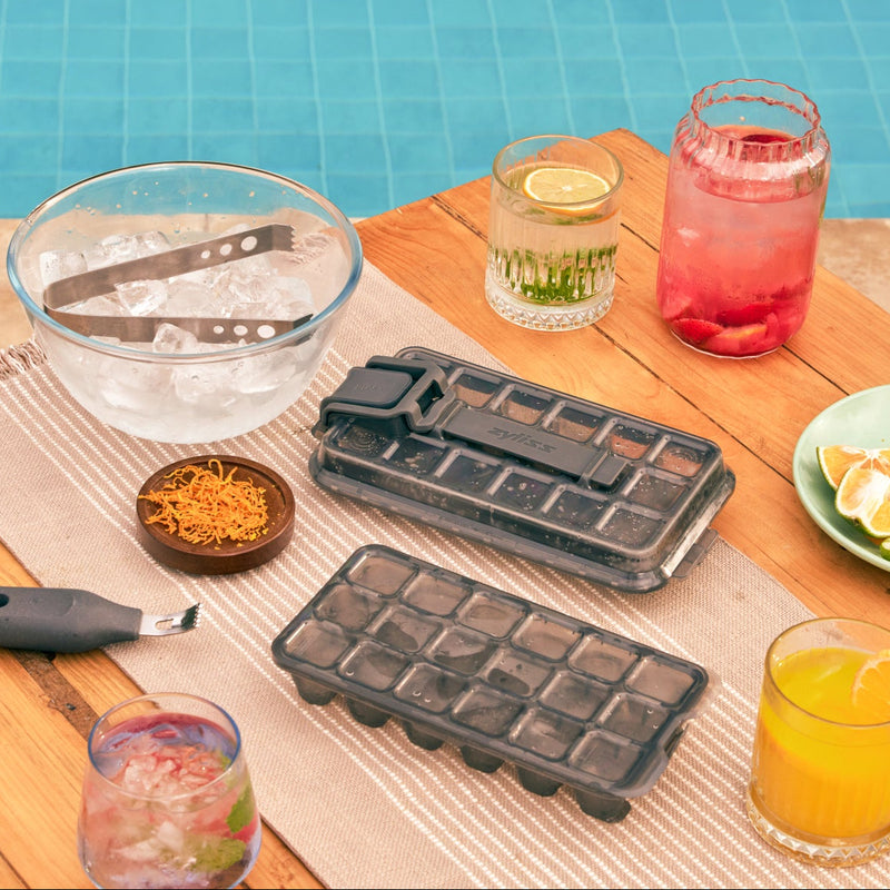 Two Zyliss Press & Pull ice cube trays beside fruit and drinks at a poolside table