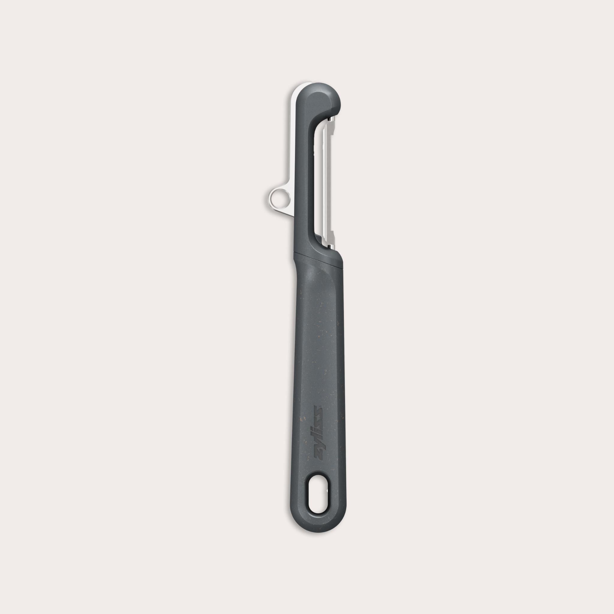 The Zyliss Swivel Peeler is black, with an ergonomic handle, straight blade, and a hole at the end. Its shown on a plain light background. 